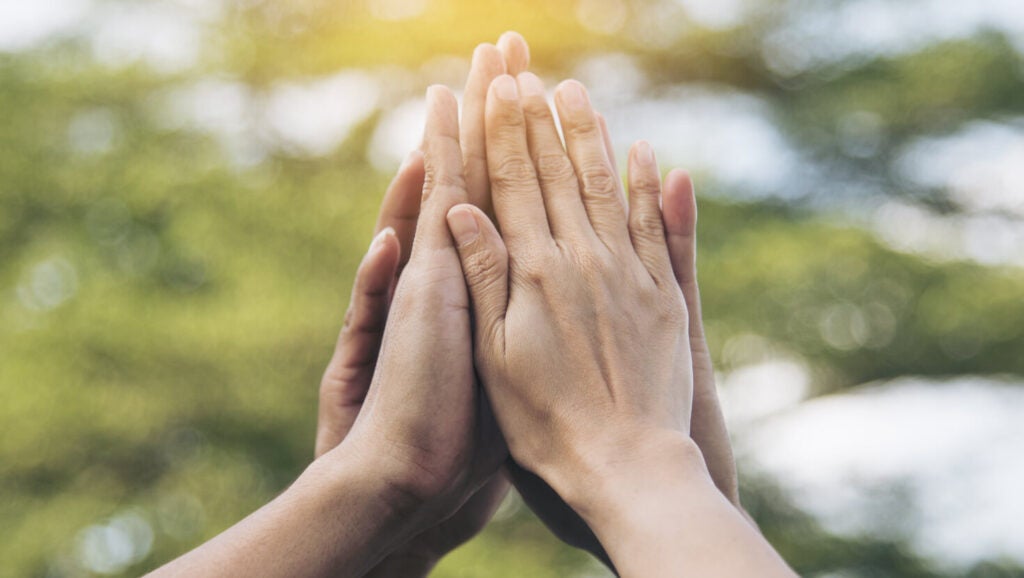 Hands high-fiving outdoors