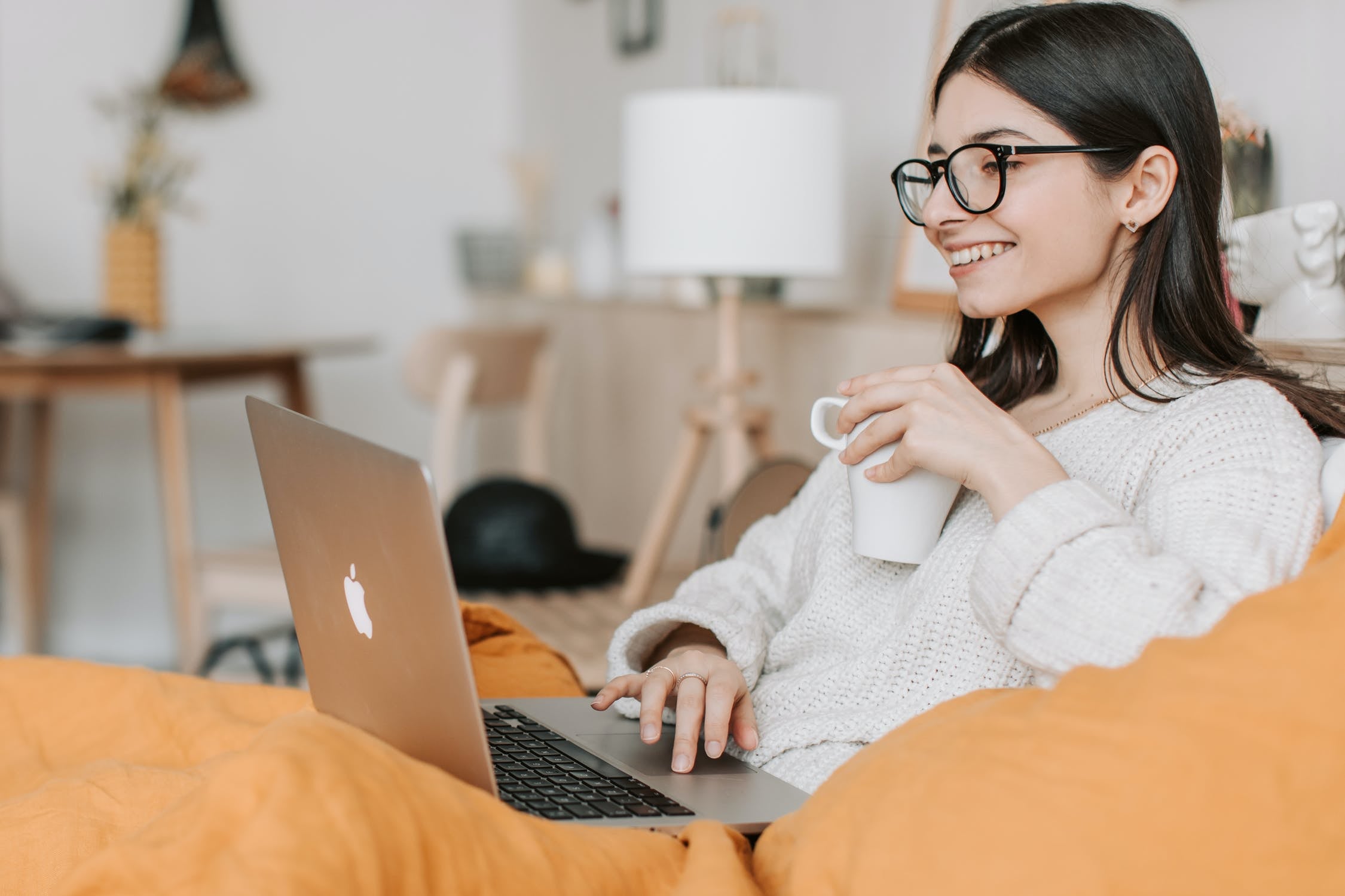 Woman with laptop and cup of coffee sitting on couch