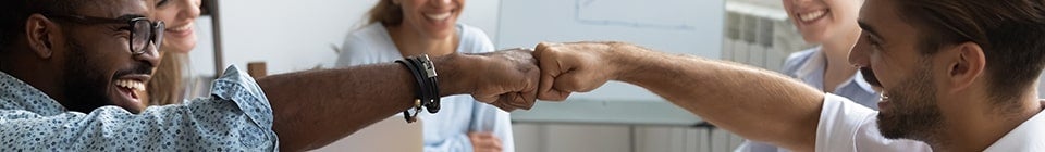 two employees bumping fists in an office meeting