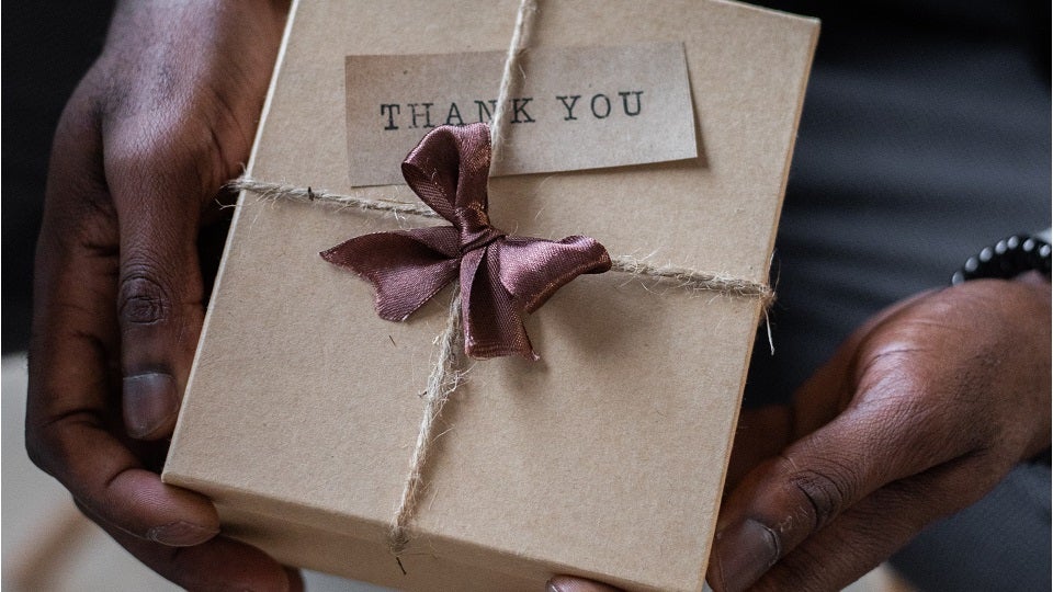 Black man holding gift box that says thank you for years of service award